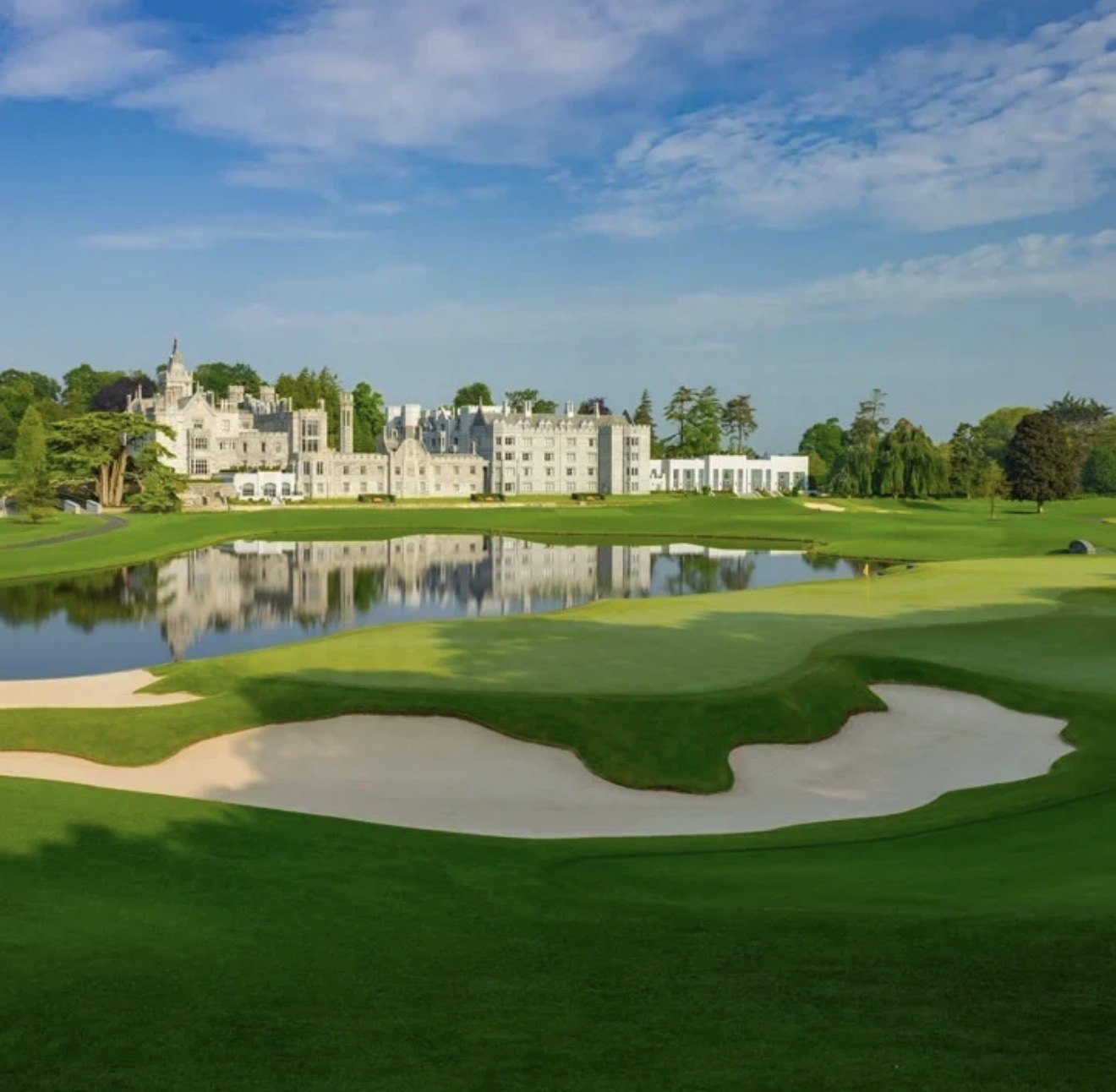 Adare Manor hotel reflected in the lake behind a large white sand bunker and green on the Adare Manor championship golf course, County Limerick, Ireland
