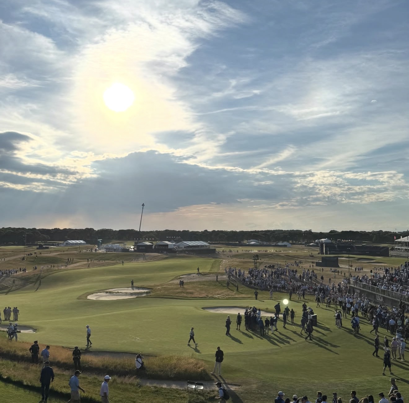US Open championship green at sunset with USGA-branded grandstands and large crowds
