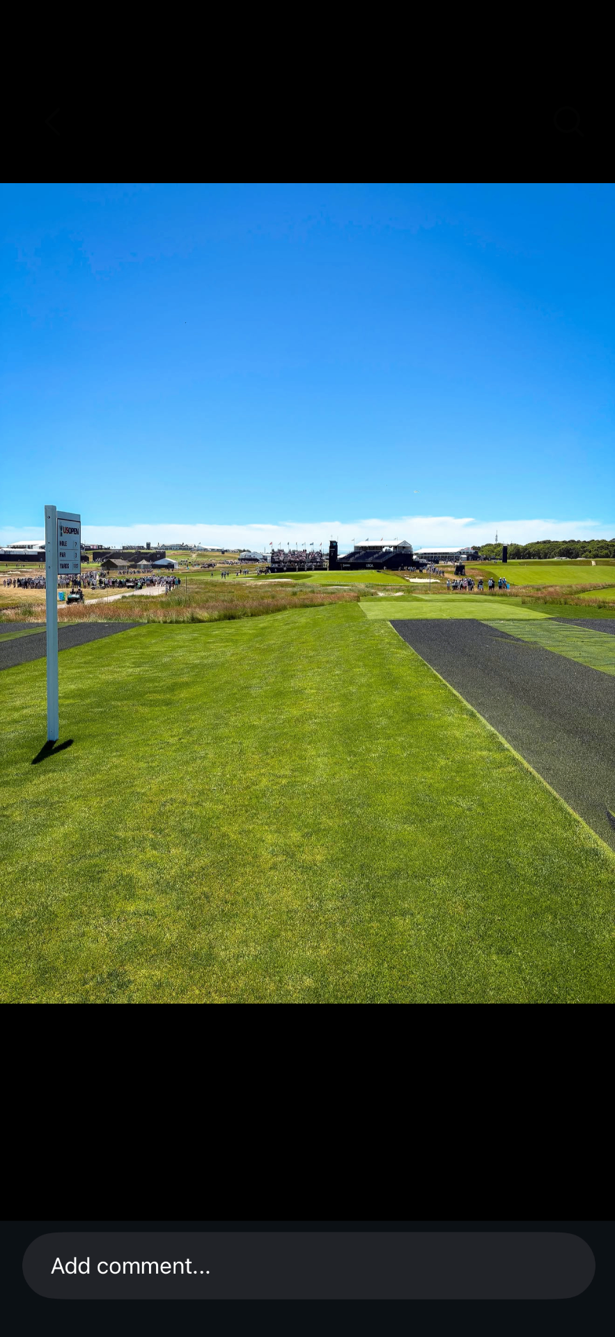 Par-3 championship tee with a US Open branded scoreboard and grandstands in the distance