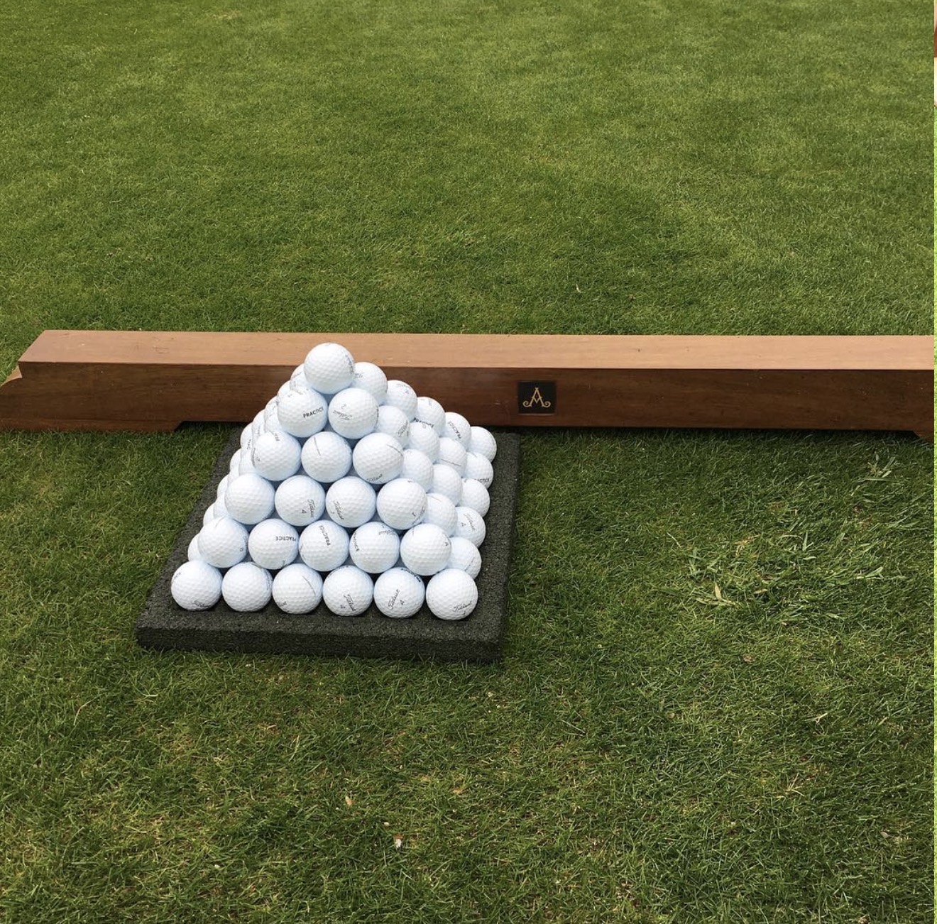 Pyramid of Titleist practice balls at Adare Manor driving range beside a beam with the Adare Manor A monogram