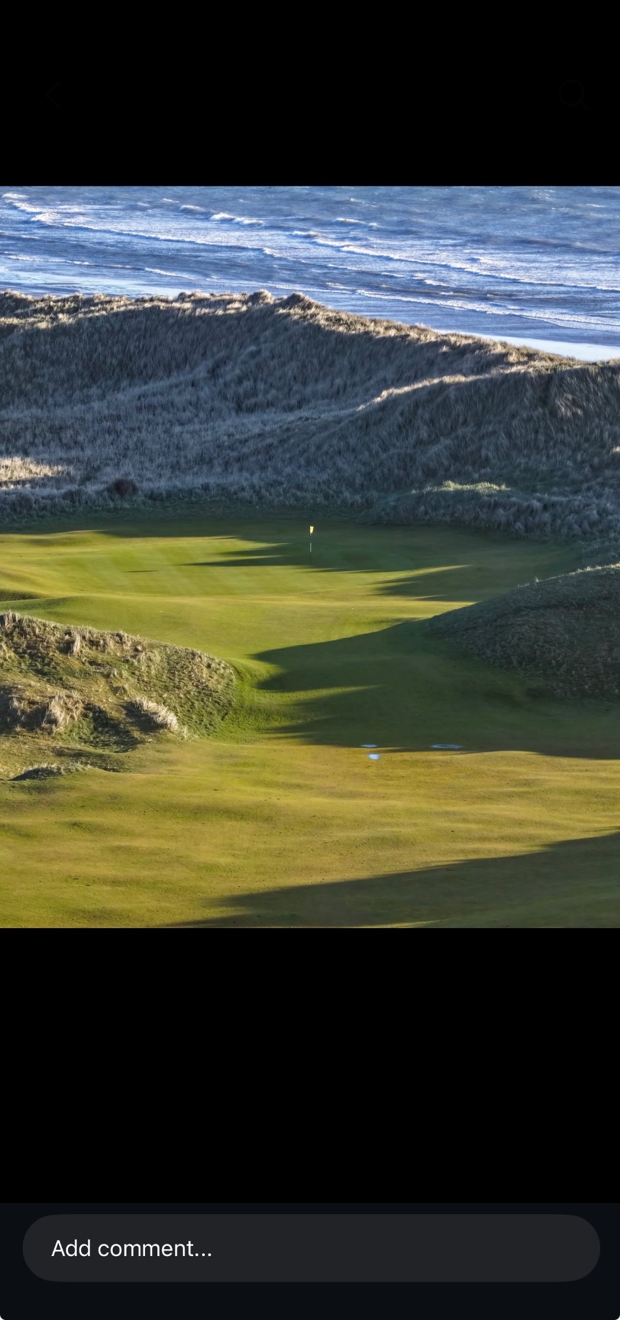 Coastal links green surrounded by dune grass with the sea in the background